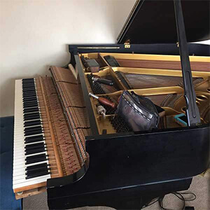 Open grand piano with its lid raised, exposing the strings and inner parts.