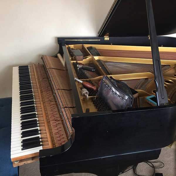 Open grand piano with its lid raised, exposing the strings and inner parts.